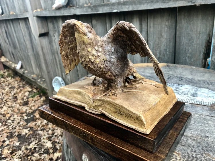 Eagle sculpture with spread wings on a book-shaped base by Lauren Noorlag